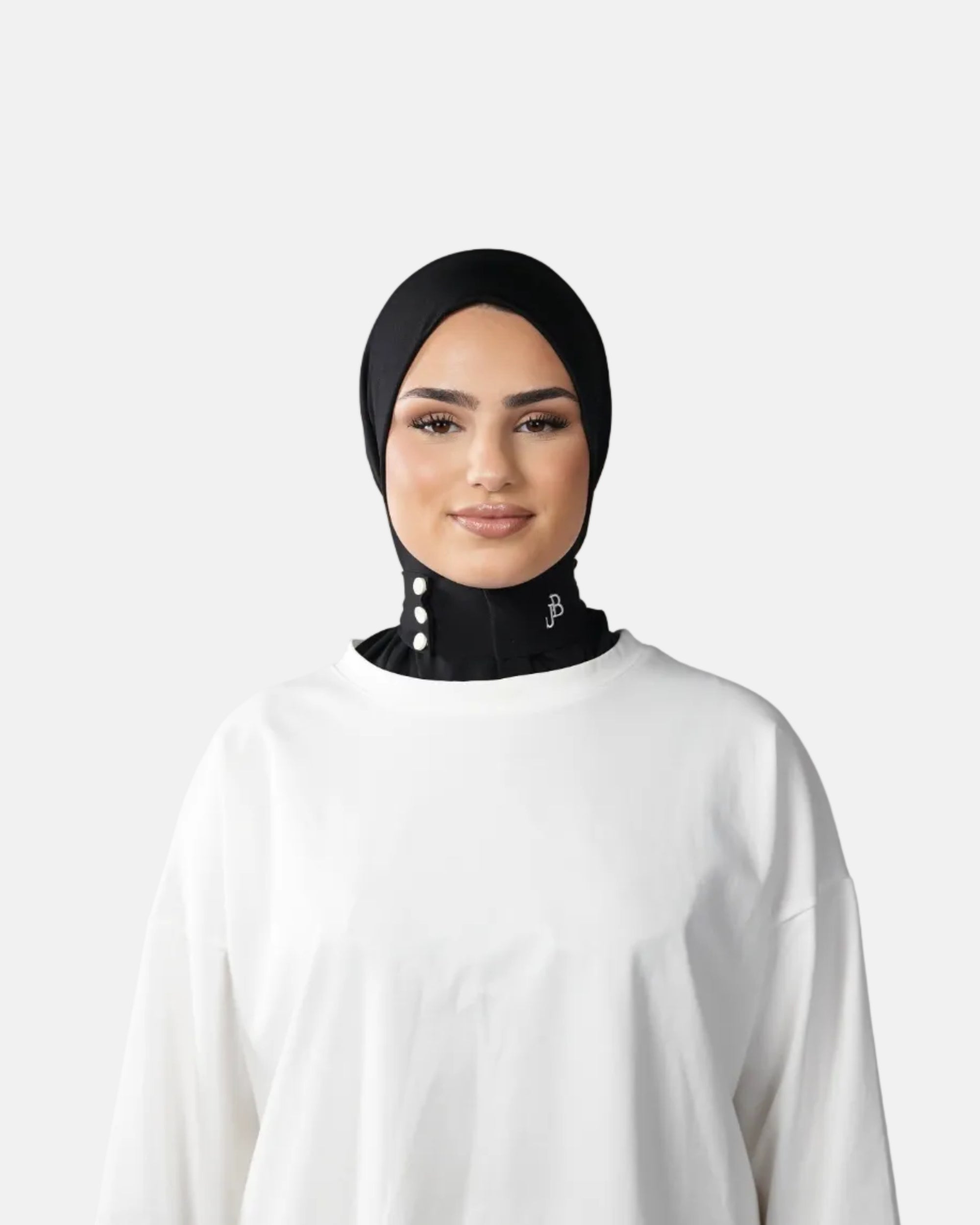 Woman wearing a black hijab and white outfit against a gray background