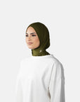 Woman wearing a green hijab and white outfit on a gray background