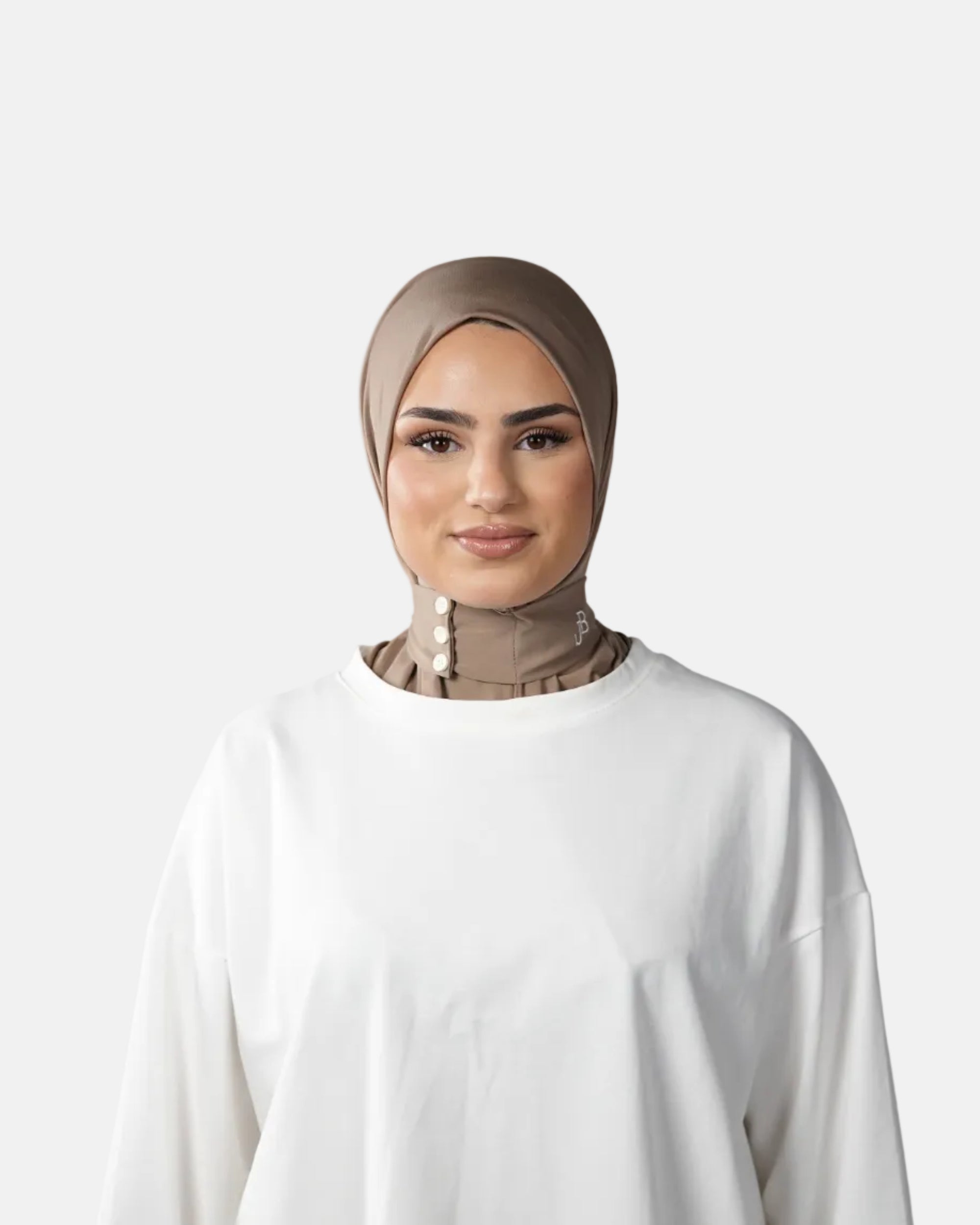 Woman wearing a beige hijab and white shirt against a gray background