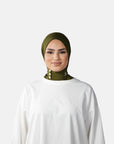 Woman wearing a green hijab and white outfit on a gray background