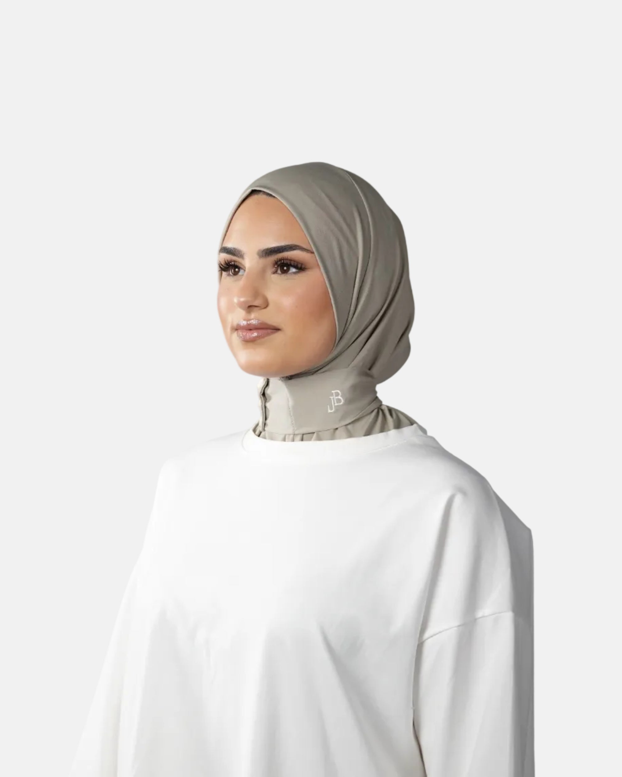 Woman wearing a beige hijab and white outfit on a gray background