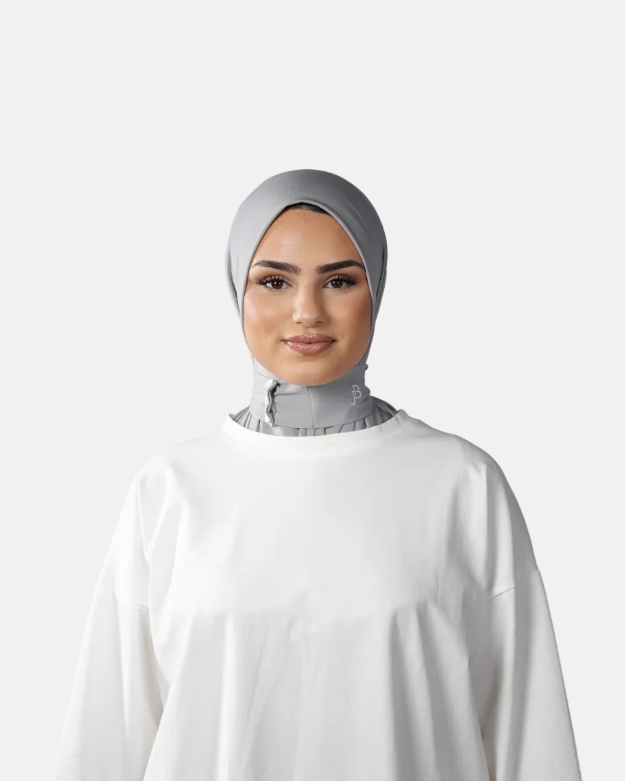 Woman wearing a gray hijab and white outfit against a gray background