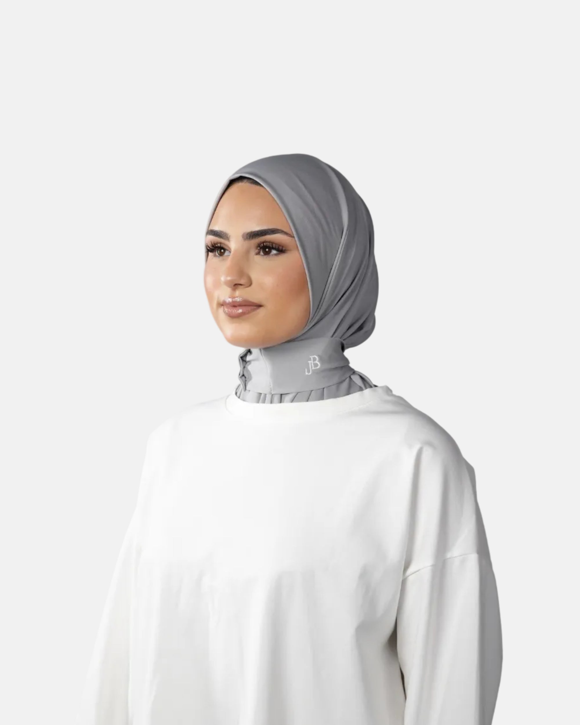 Woman wearing a gray hijab and white top against a gray background